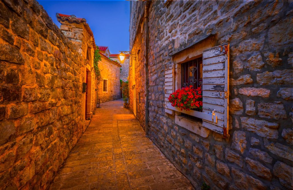 Charming stone alleyway with a flowered window in twilight