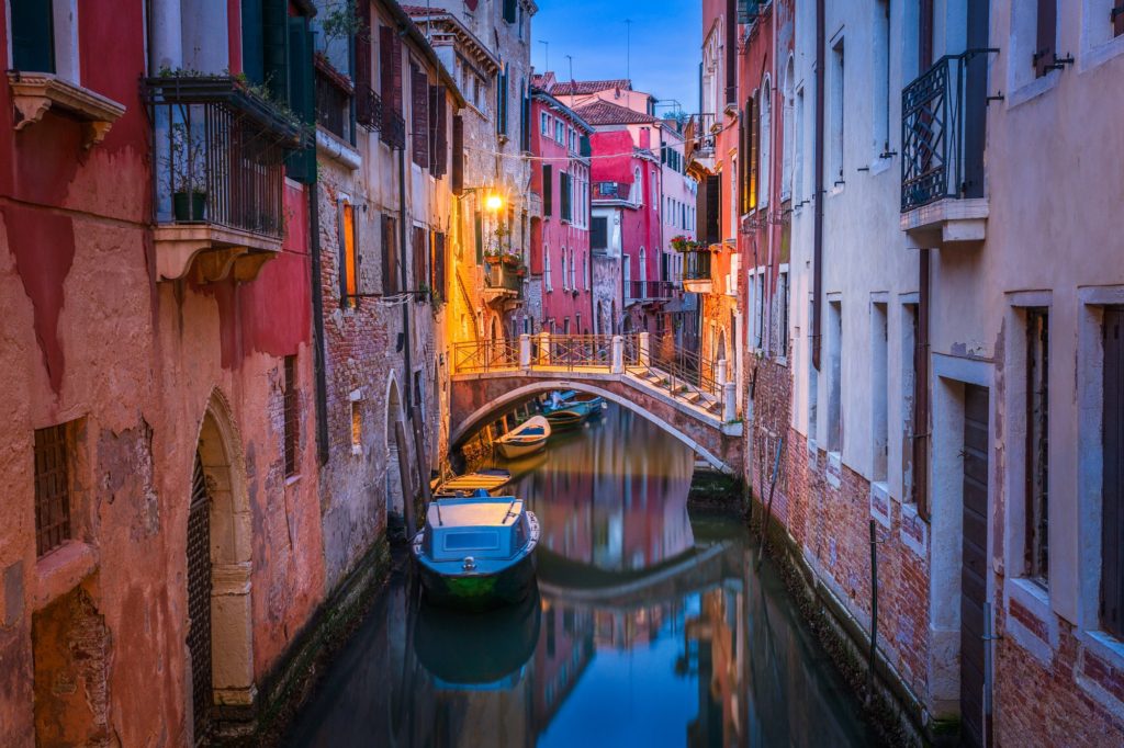 Venice canal illuminated during blue hour, Italy